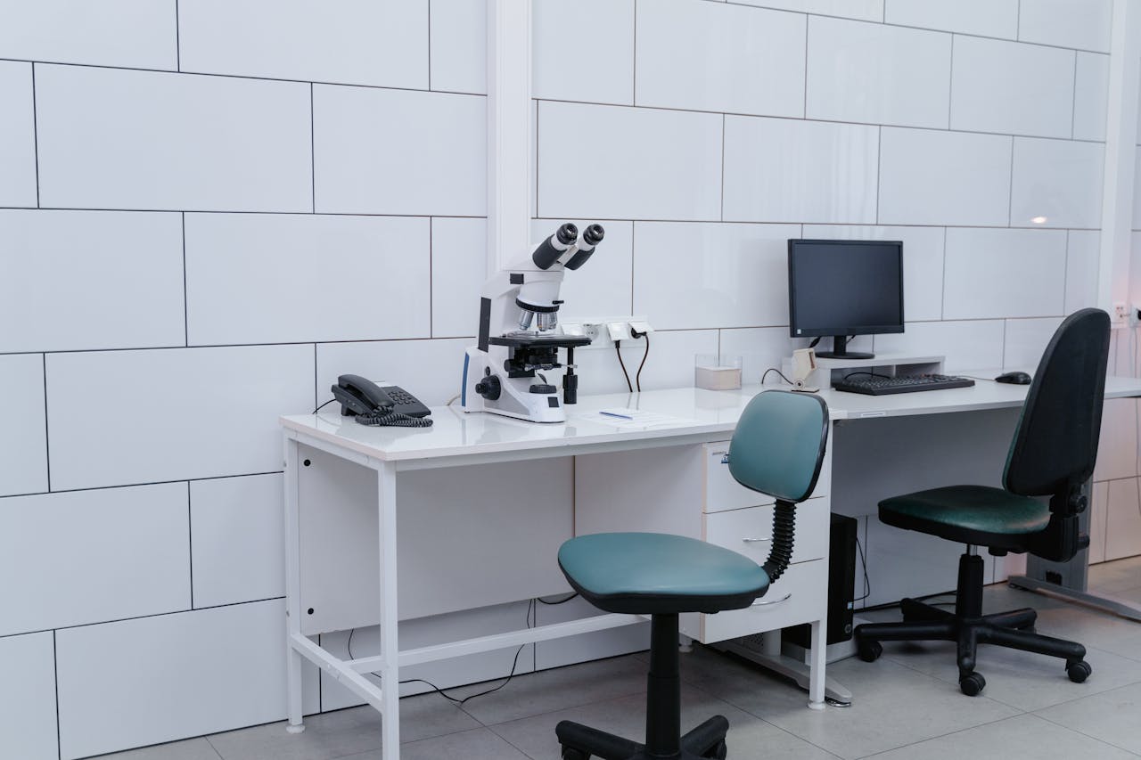 Modern laboratory with microscope, monitor, and office equipment on desk.